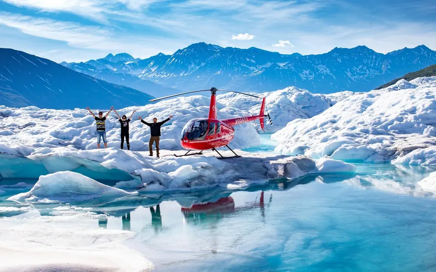 A helicopter landed on a snowfield with mountains behind, Alaska
